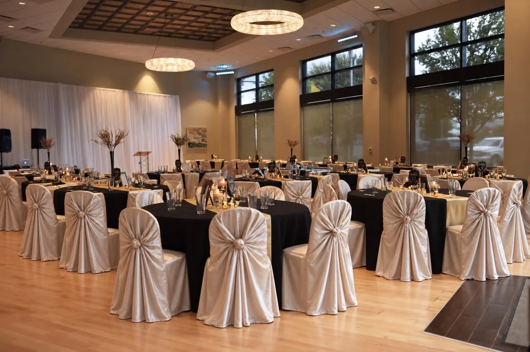 Midtown Ballroom set for a formal dinner reception with black tablecloths and ivory chair covers